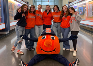 The all-girl graduating cohort of Otto the Oranges poses with their coach, Julie Walas, and Otto. The women became Otto to connect with people and make their days. 
